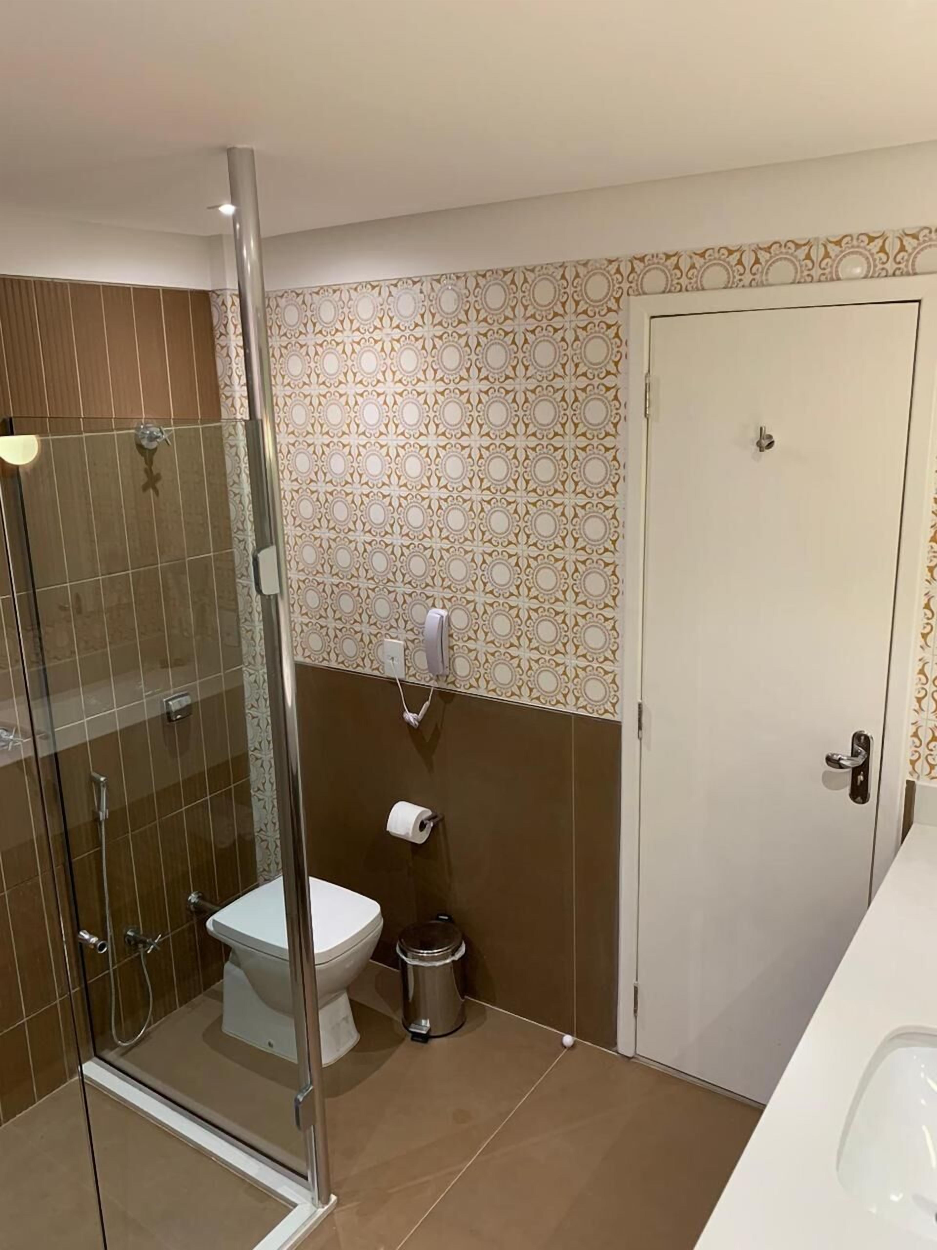 Un baño con ducha de mampara, inodoro y lavamanos.