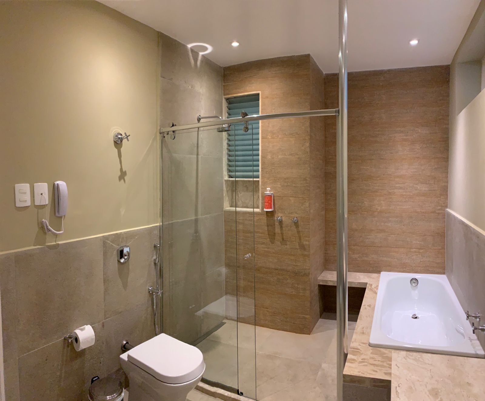 Un baño moderno con ducha envuelta en vidrio, inodoro, bañera y tocador con espejo.