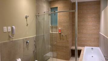Un baño moderno con ducha envuelta en vidrio, inodoro, bañera y tocador con espejo.
