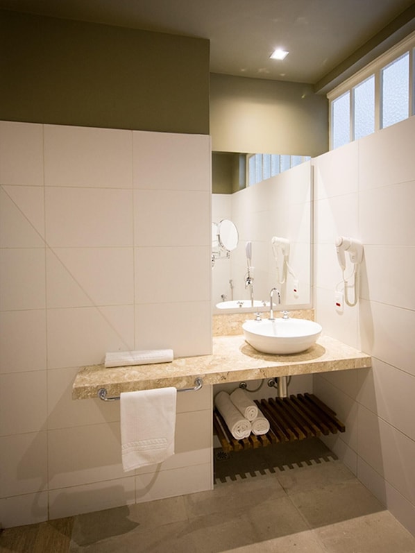 Un baño moderno con un lavamanos grande, espejo y toallero.
