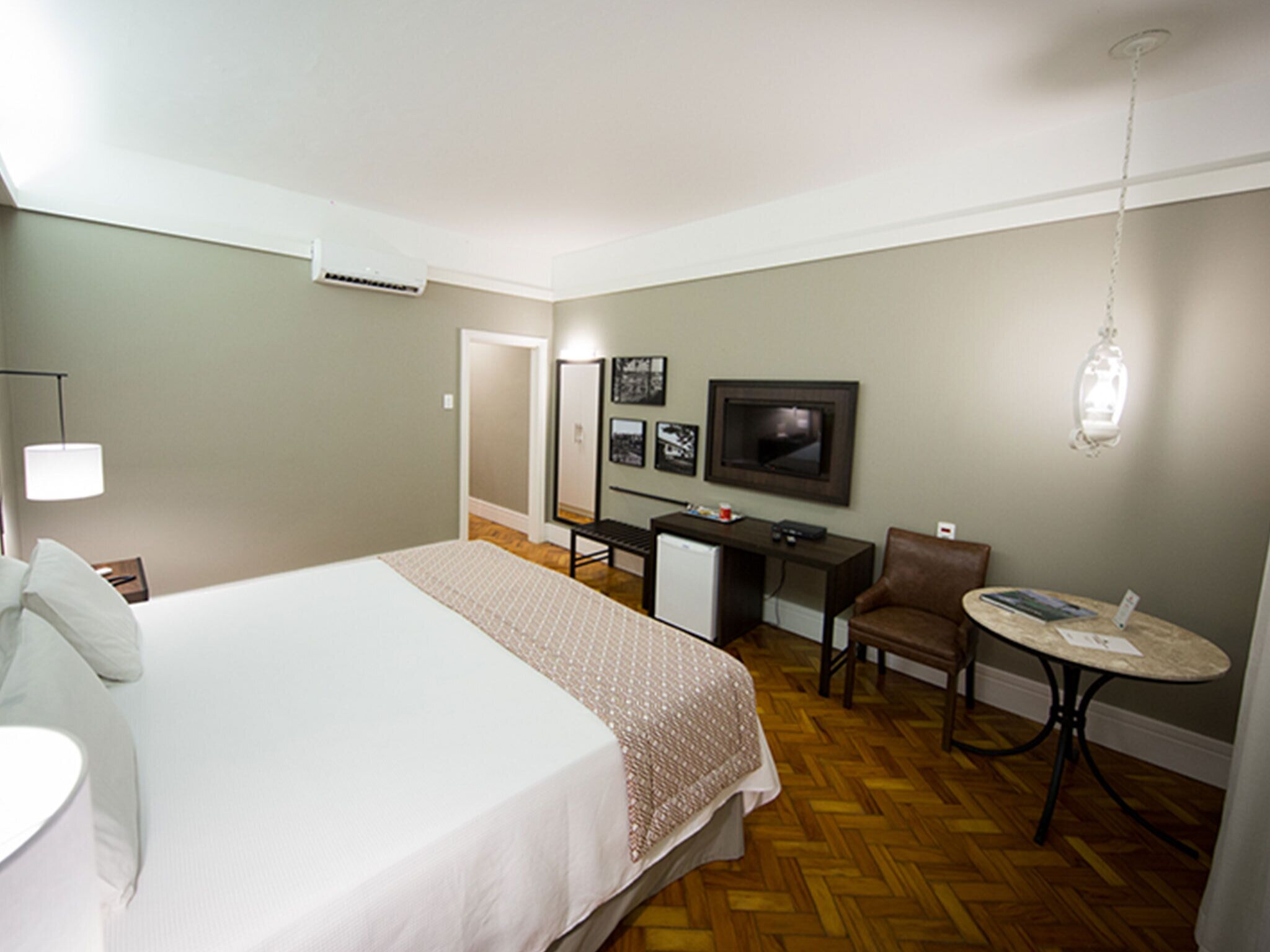 A hotel room with a bed, desk, chair, television, and a small table.