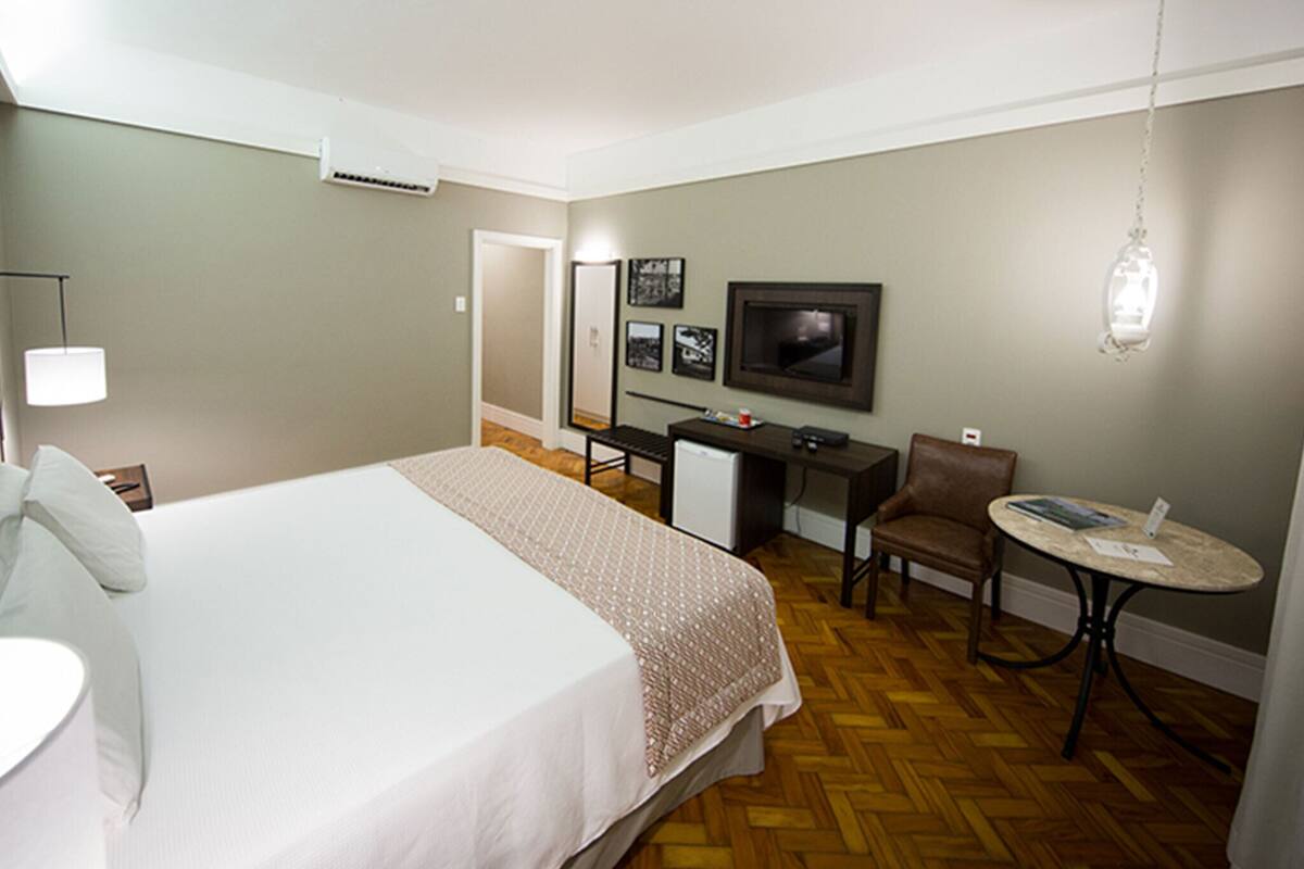 Une chambre d’hôtel équipée d’un lit, d’un bureau, d’une chaise, d’une télévision et d’une petite table.