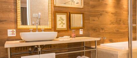 Un baño moderno con un espejo grande, un lavabo, una ducha y un perchero para toallas.