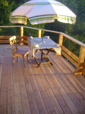 A wooden deck with a table and chairs, an umbrella, and a railing. - Savoyard chalet overlooking Lac LÉMAN (Armoy)