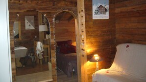Quarto de cabana de madeira com cama, espelho, abajur e uma placa indicando 'Chalet Dallidet'.