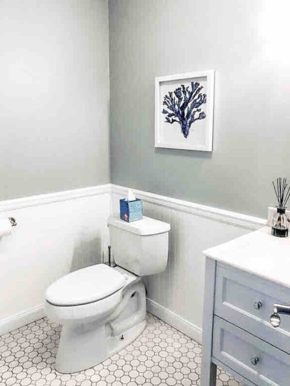 Une salle de bain avec des toilettes, un lavabo et une œuvre d’art encadrée accrochée au mur.