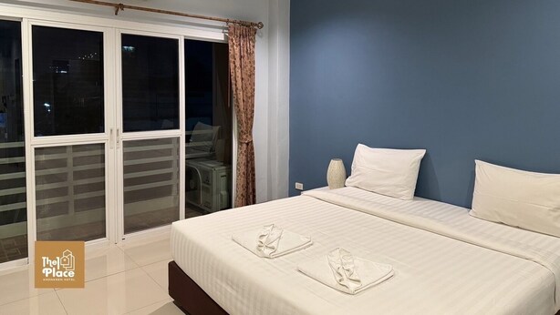 A hotel room with a bed, a window with curtains, an air conditioning unit, and a view of the outside. - The 1 Place Khonkaen (Khon Kaen)