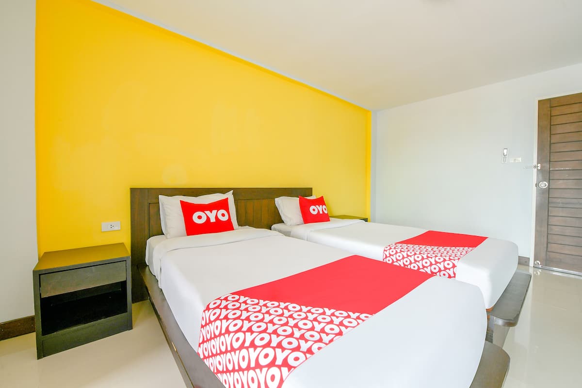 A hotel room with two beds, each with a red and white bedspread, and a yellow accent wall.