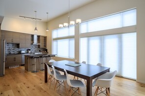 A modern kitchen with a central island, bar stools, and a dining table with chairs. - Just completed 4 bedroom, 5 bathroom modern Town home, pool table, sleeps 10 (Golden)