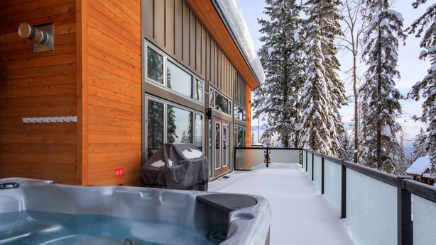 A wooden building with a hot tub on a snowy deck, surrounded by snow-covered trees. - Just completed 4 bedroom, 5 bathroom modern Town home, pool table, sleeps 10 (Golden)