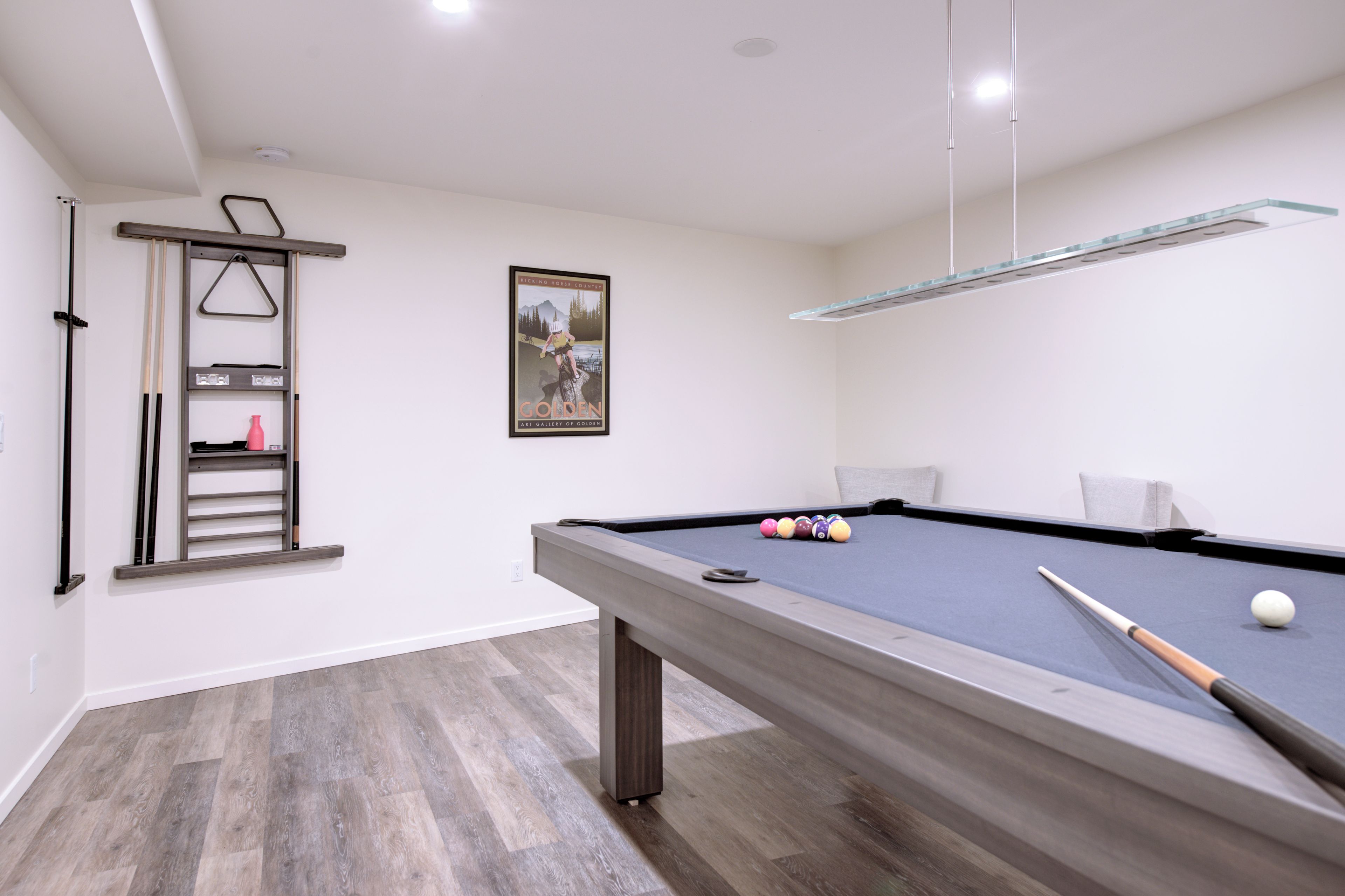 Une table de billard avec des billes, une queue de billard et une échelle appuyée contre le mur.