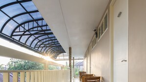 Un couloir avec un plafond en verre, des chaises en bois et une porte sur le côté droit.