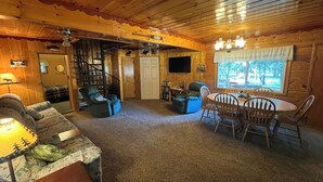 A log cabin interior with a living room, dining area, and a staircase. - Gateway To Yellowstone Park And Outdoor Adventure. FREE internet and cleaning. (Island Park)
