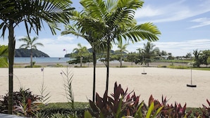 A beach with palm trees, a sandy area, and a view of the sea. - Luxury Los Sueños Condo - Marina, Pools & Golf. Fishermans Paradise! (Los Suenos)