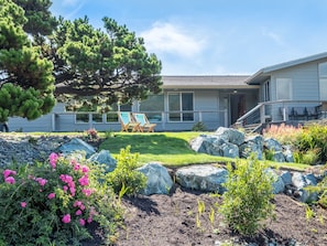 A residential property with a well-maintained garden, large rocks, and two lounge chairs.