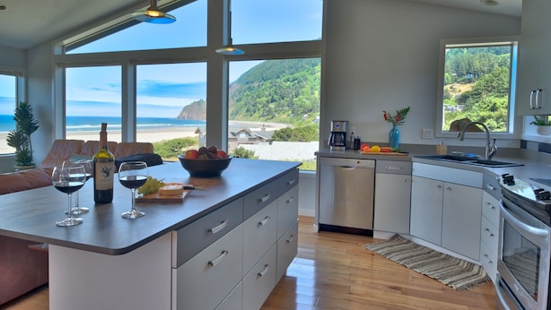 Une cuisine moderne dotée de grandes fenêtres, d’un îlot central et offrant une vue sur la plage.