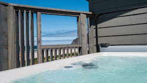 Un bain à remous avec une terrasse en bois et vue sur l’océan.