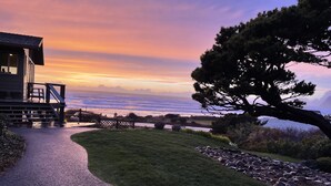 Une propriété située sur la côte, dotée d’une terrasse avec vue sur l’océan, d’une pelouse bien entretenue et d’un grand arbre.