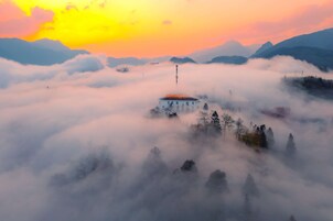 Un edificio rodeado de nubes bajo un cielo despejado.