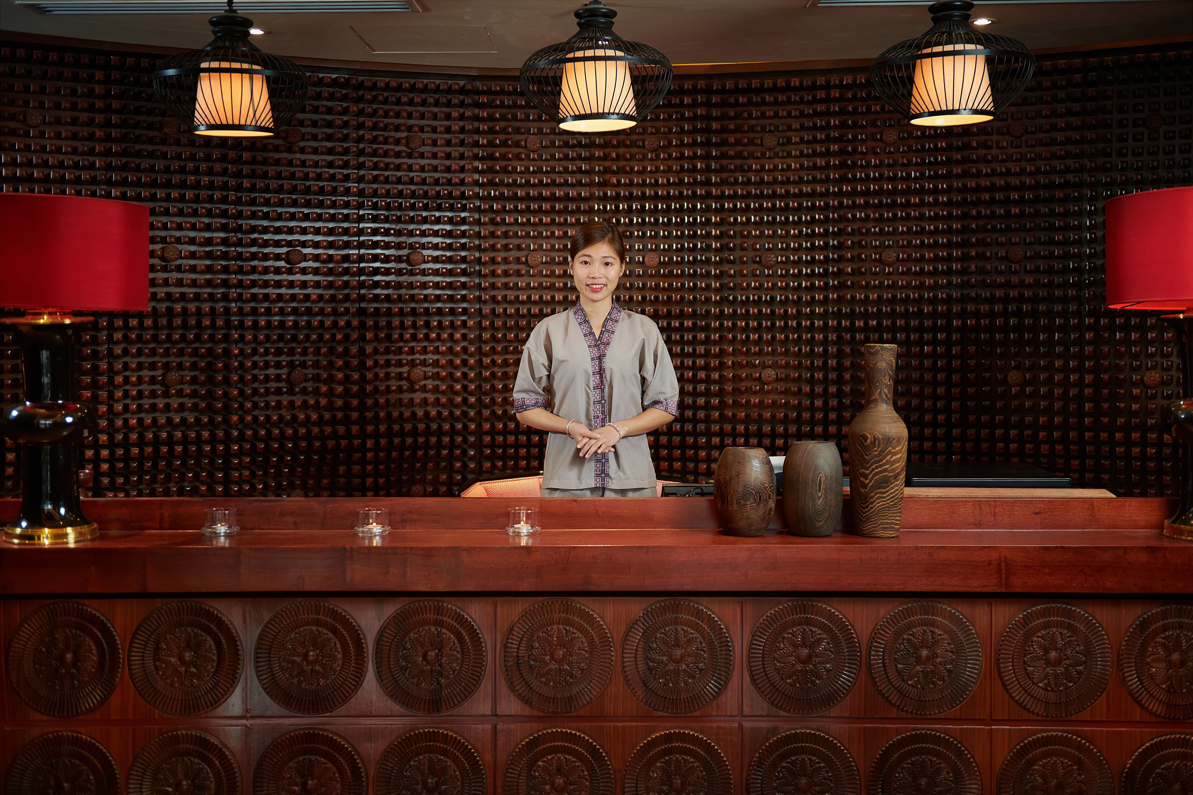 A bar area with a wooden wall, a bar counter, and two red lamps.