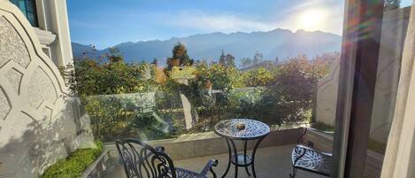 Un balcon avec deux chaises en métal et une table, donnant sur un paysage montagneux.