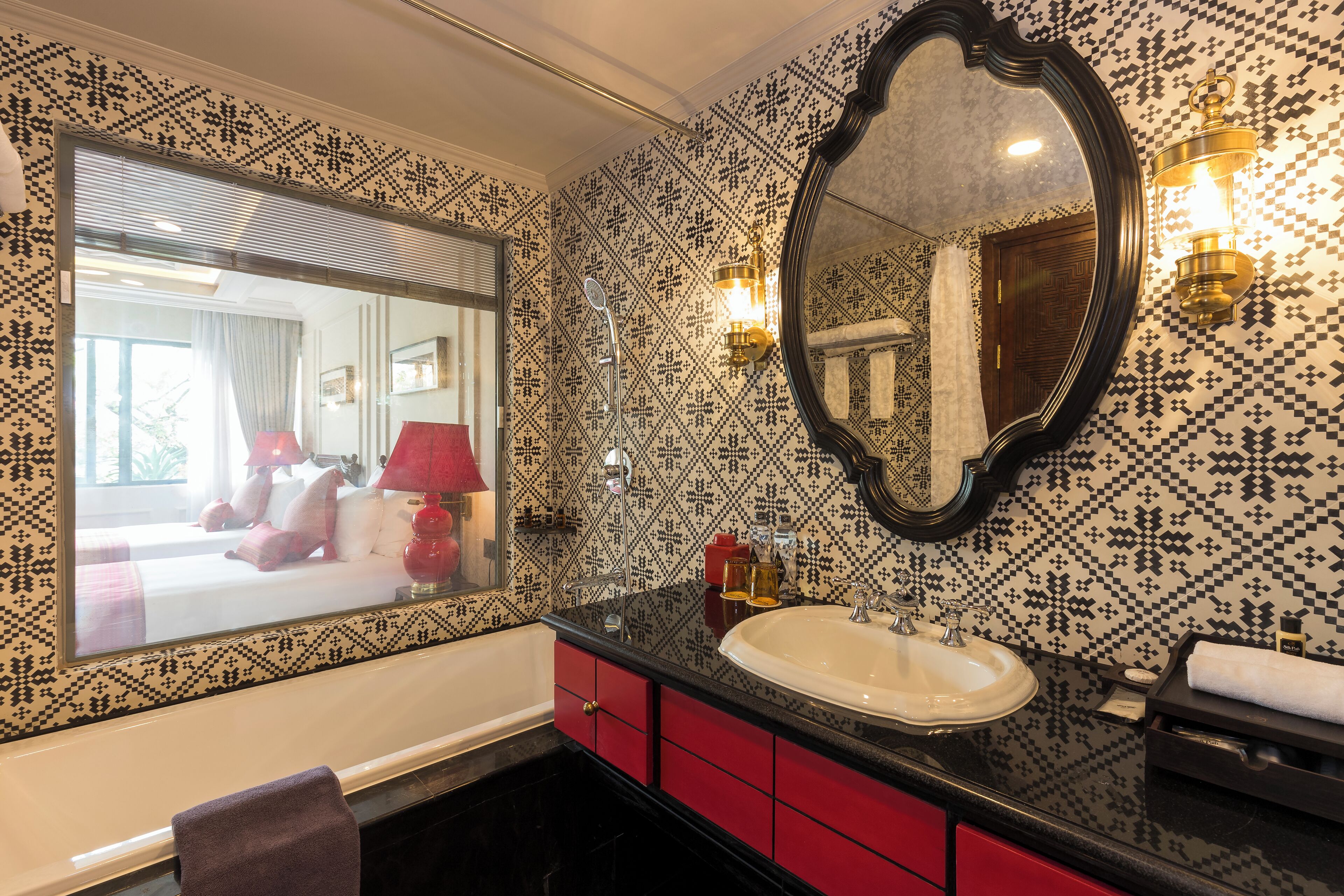 A bathroom with a large mirror, a sink, and red cabinets.
