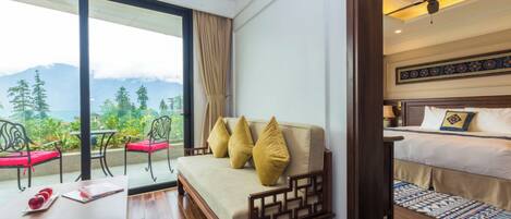 Una habitación de hotel con sofá, cama, escritorio y vistas a montañas.