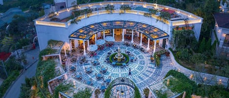 Un hotel circular con un patio central, rodeado de exuberante vegetación y un camino serpenteante.
