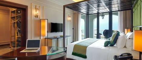 A hotel room with a bed, a desk with a laptop, a television, and a view of the outdoors.