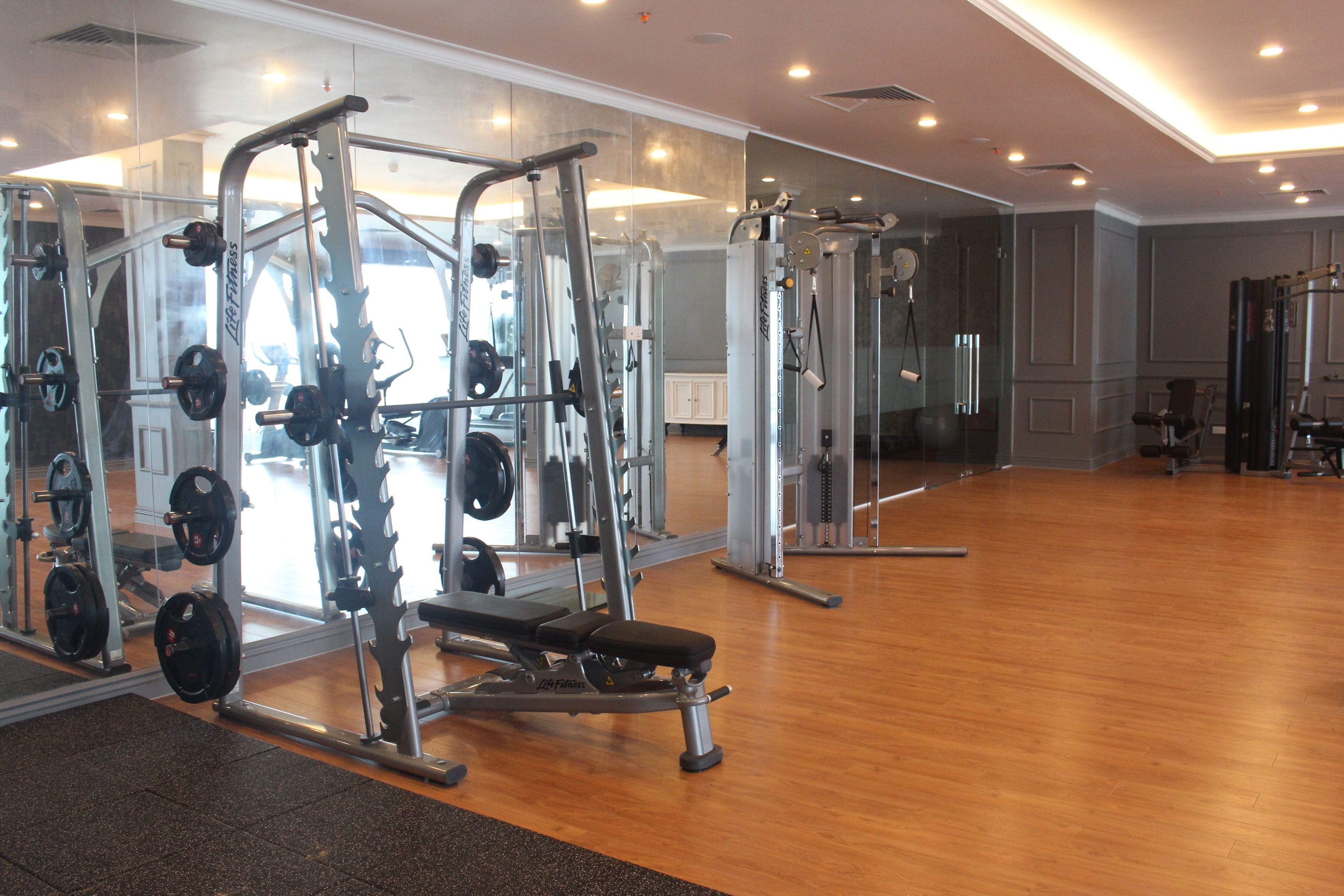 A gym with various exercise machines, a bench, and weight racks.