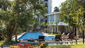 A swimming pool with lounge chairs, surrounded by greenery and a modern building. - GAIA Hotel & Residence Phu Quoc (Phu Quoc)