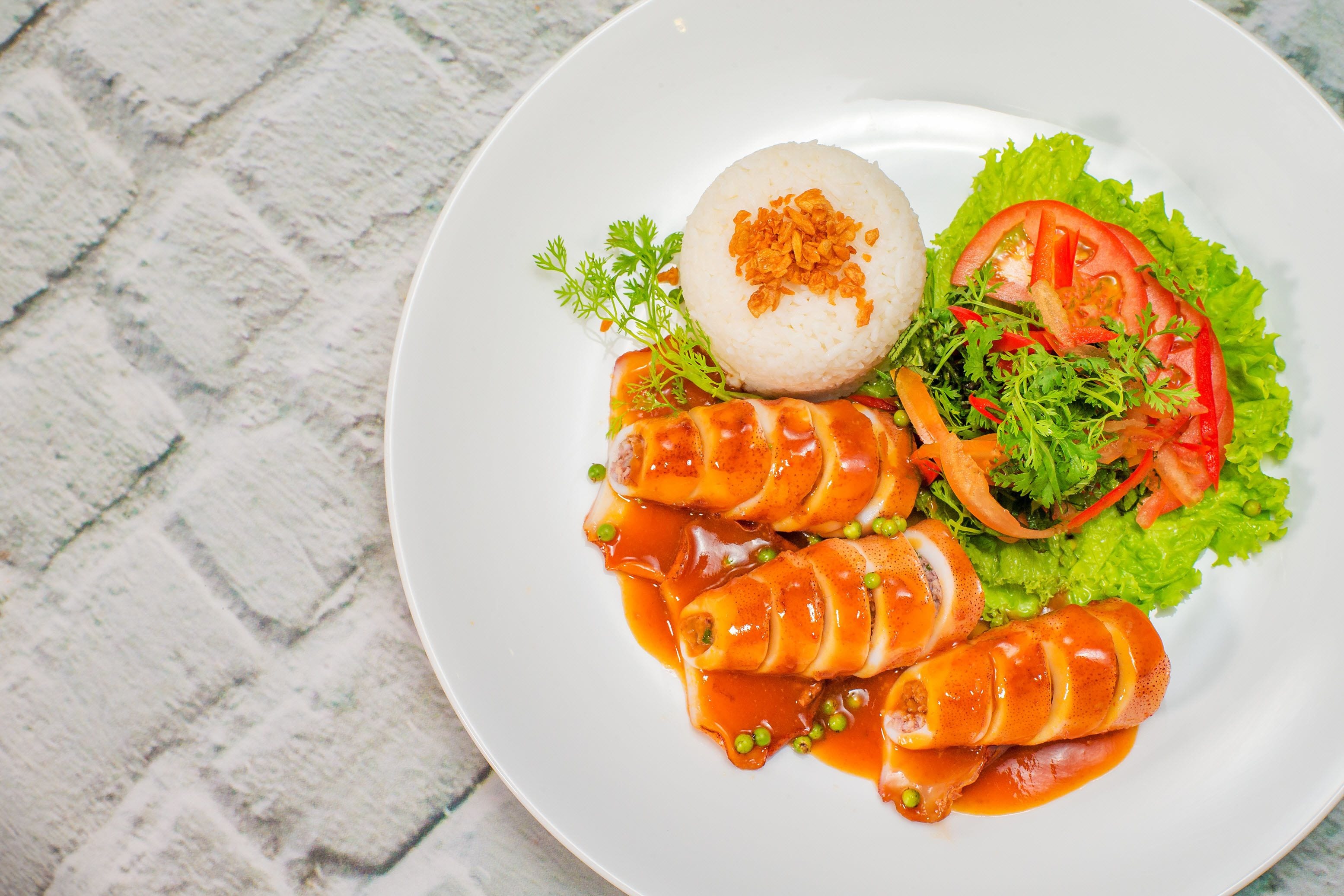 A plate of food with rice, vegetables, and a sauce.