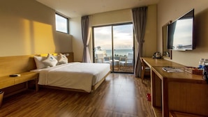 A hotel room with a bed, a desk, a TV, and a balcony with a view of the sea. - GAIA Hotel & Residence Phu Quoc (Phu Quoc)
