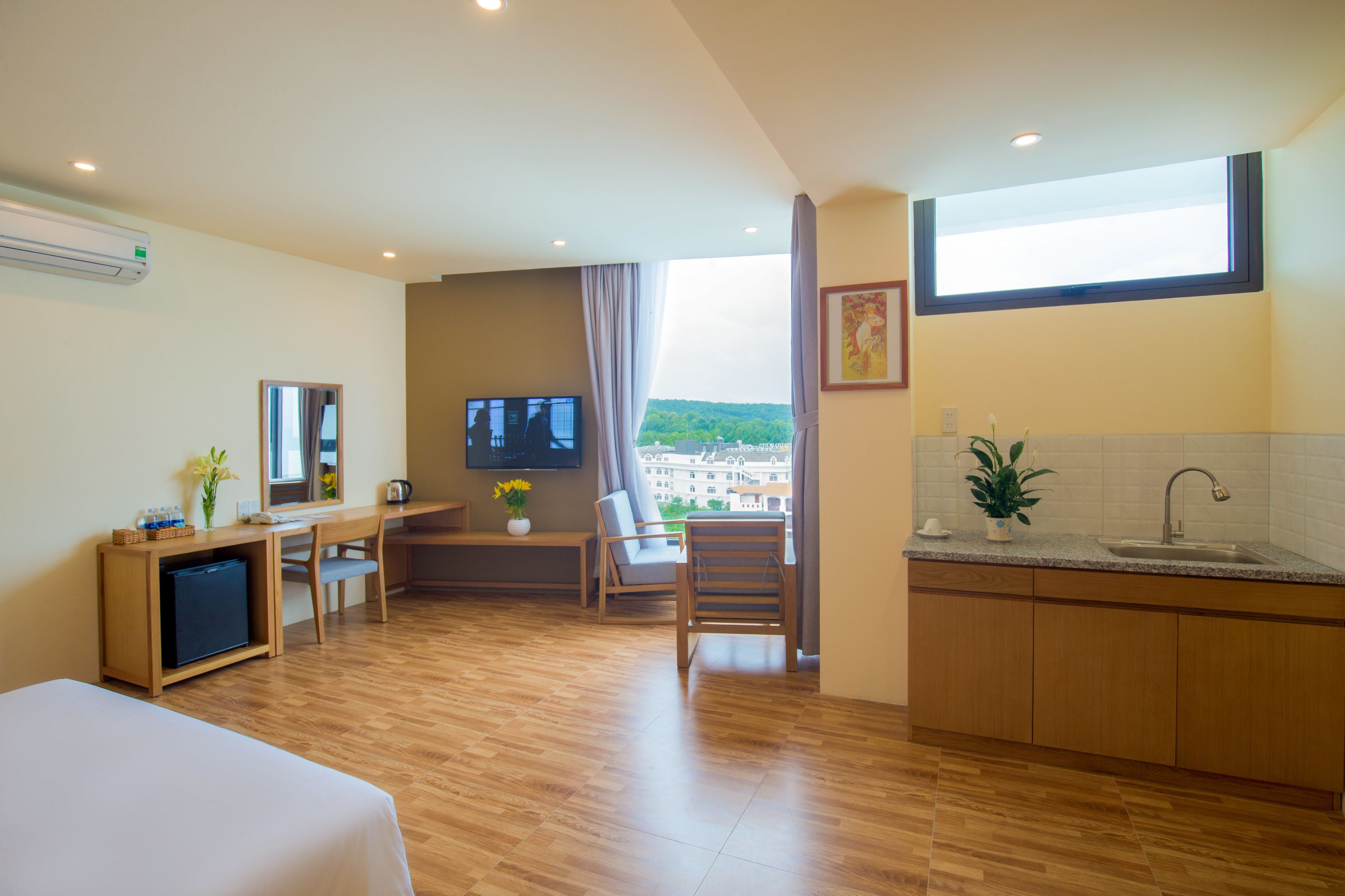 Habitación de hotel con cama, escritorio, televisión y vista a un edificio a través de una ventana.