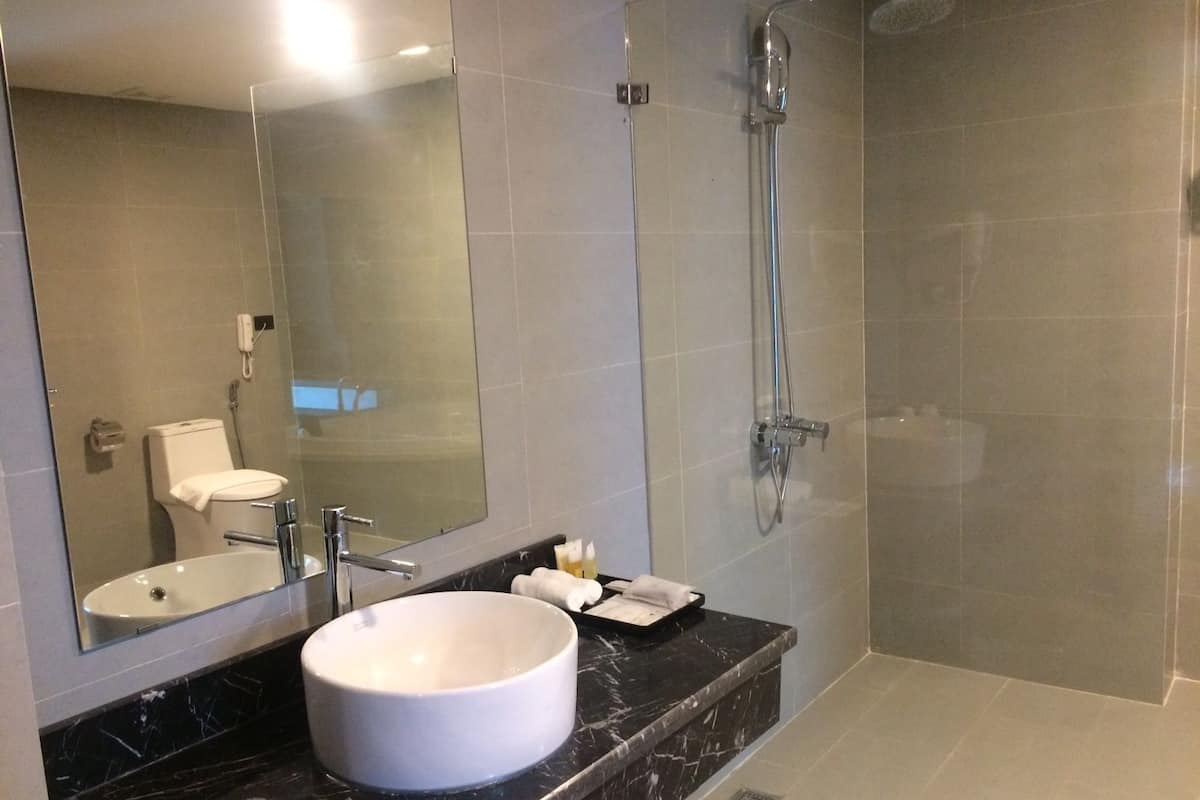 Ein modernes Badezimmer mit rundem Waschbecken, einem Spiegel, einer Toilette und einer Duschkabine.