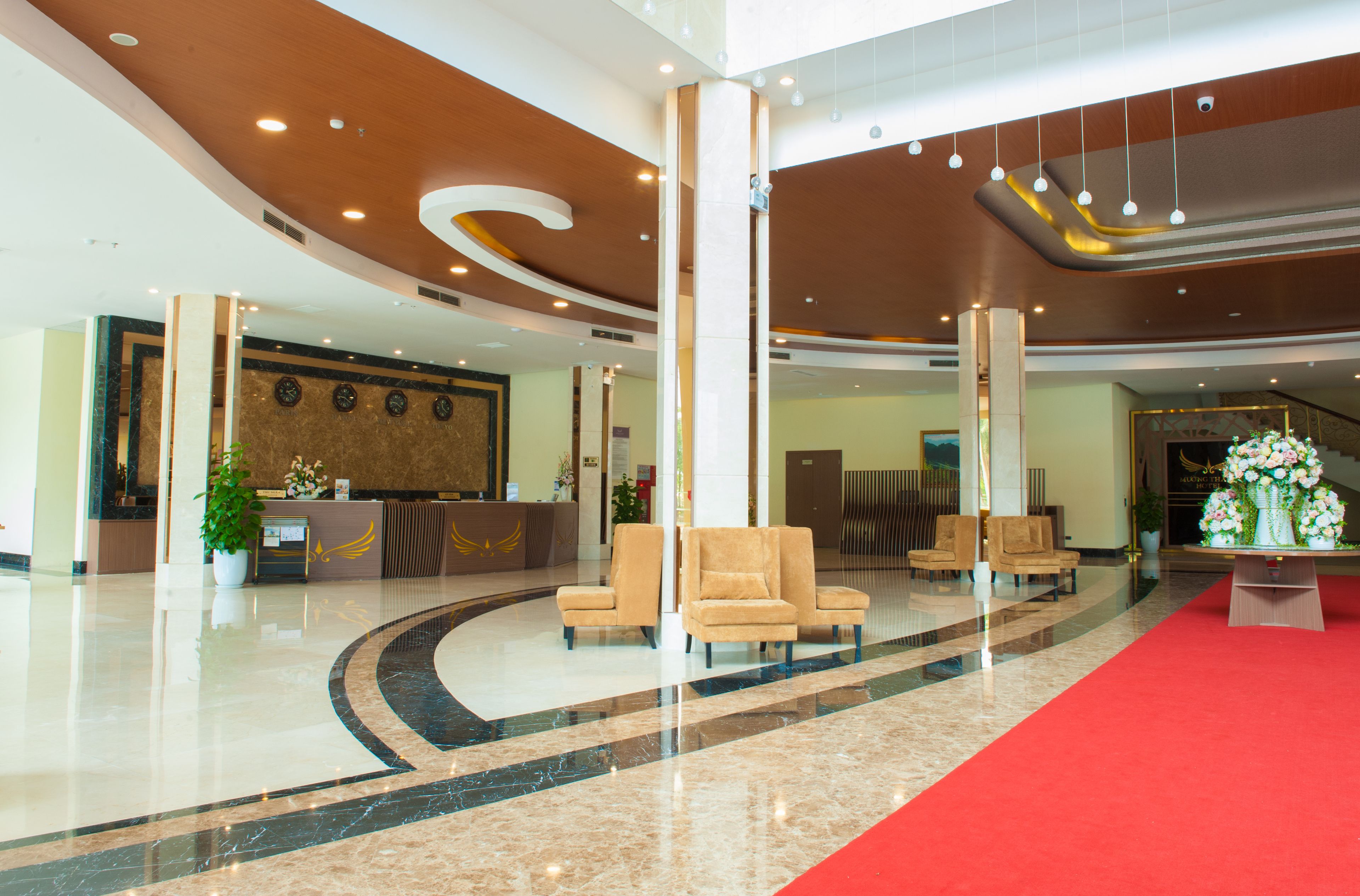 A spacious lobby with a reception desk, seating area, and a red carpet.