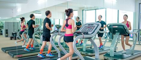 Un gimnasio con cintas de correr, espejos y equipo de ejercicio.