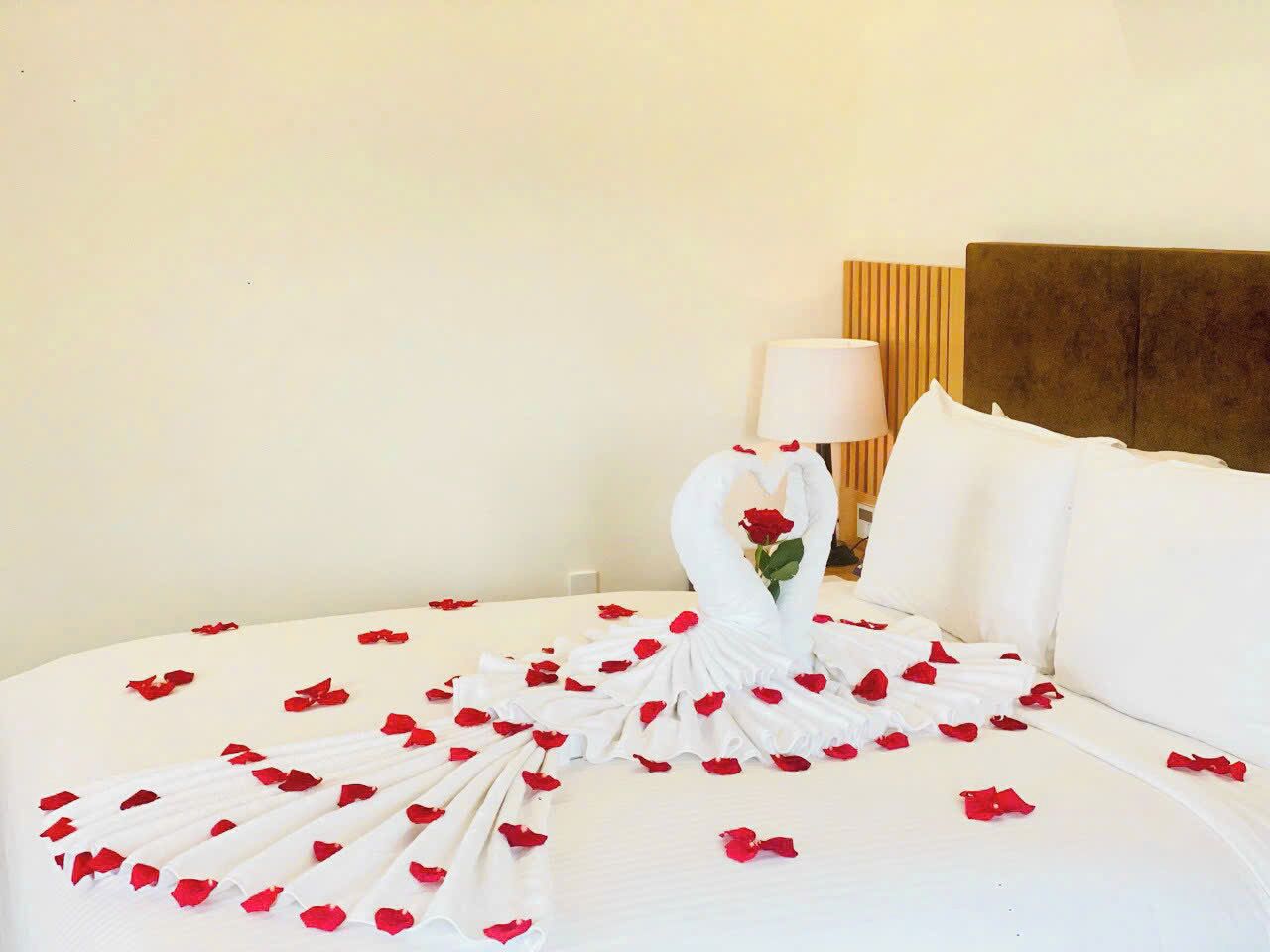 Ein ordentlich gemachtes Bett mit Rosenblättern und einem schwanenförmigen Kopfkissen.