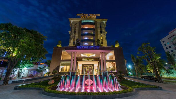 Ein Hotel mit markantem Eingang, einem Brunnen und einem Schild mit der Aufschrift "Happy New Year".