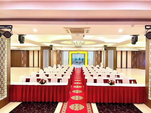 A conference room with rows of white chairs, red tablecloths, and a red carpet leading to a bright exit. - Muong Thanh Quy Nhon Hotel (Quy Nhon)