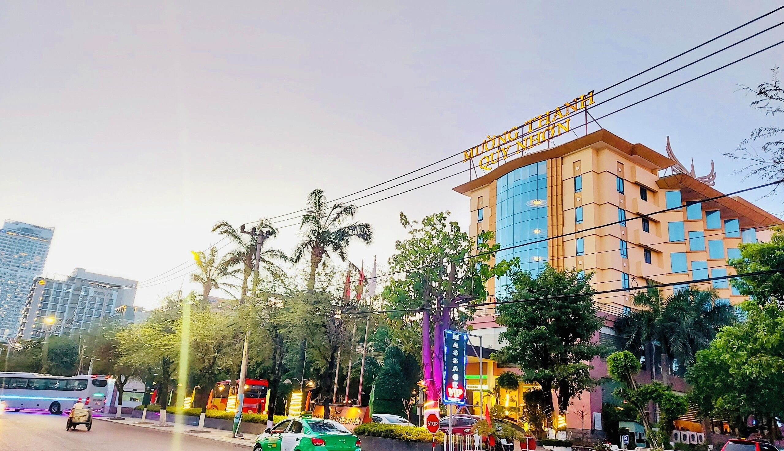 A multi-story hotel with a prominent sign, surrounded by palm trees and urban infrastructure.