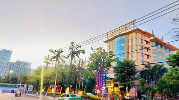 A multi-story hotel with a prominent sign, surrounded by palm trees and urban infrastructure.
