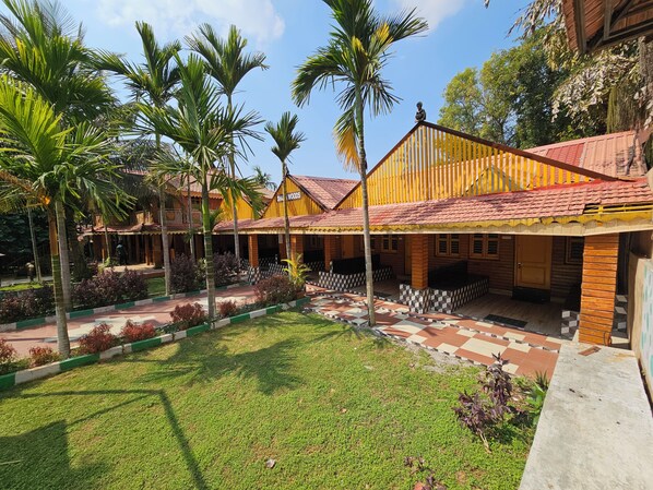 A hotel with a covered outdoor area, palm trees, and a tiled walkway.