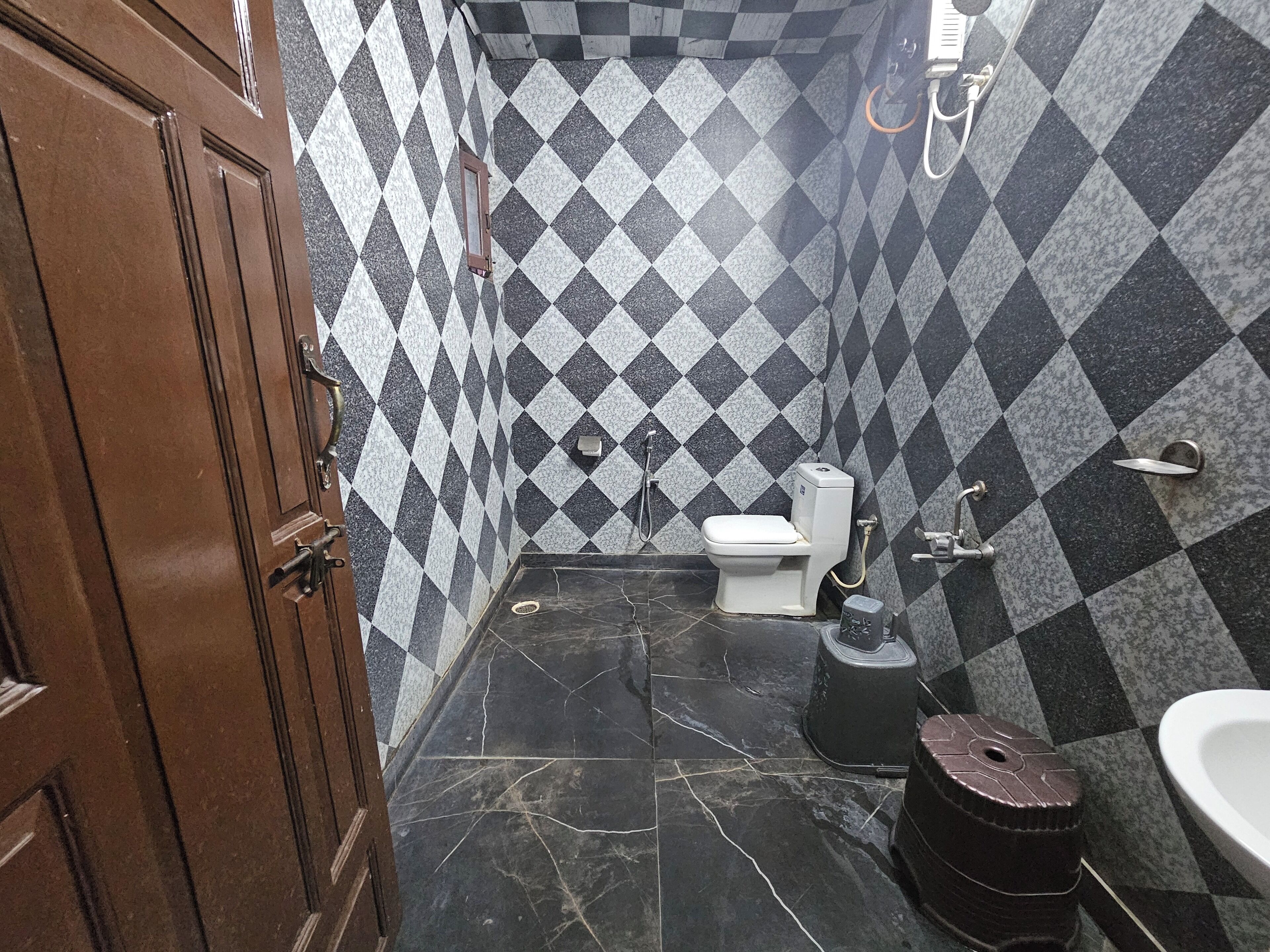 Un baño con suelo de baldosas a cuadros, un inodoro, un lavabo y una ducha.