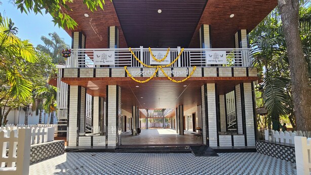 A covered outdoor area with a checkered floor, white railings, and a balcony with yellow garlands. - Ankit Vista Green Village (Nelamangala)
