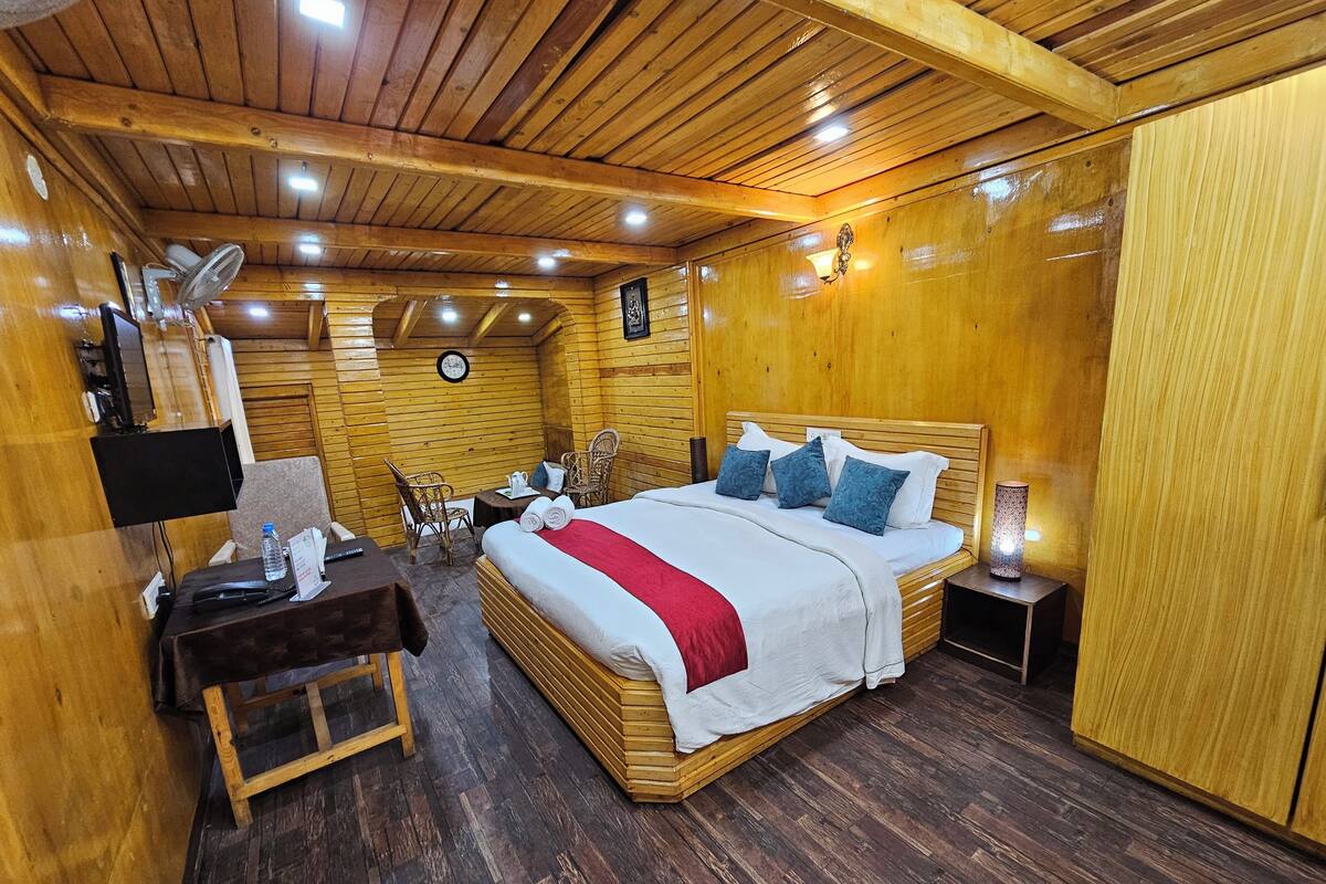 A wooden cabin-style room with a large bed, a desk, and a chair.