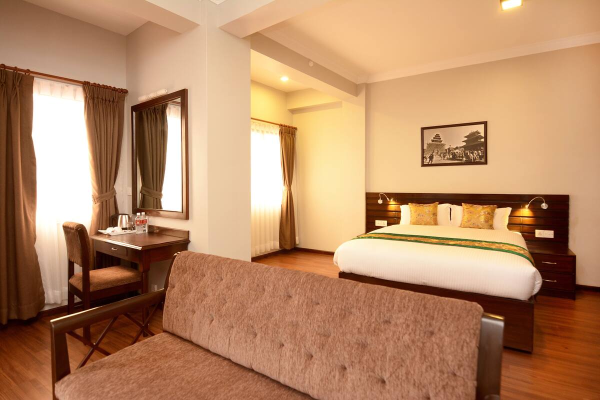 A hotel room with a bed, a desk, a chair, and a large window with curtains.