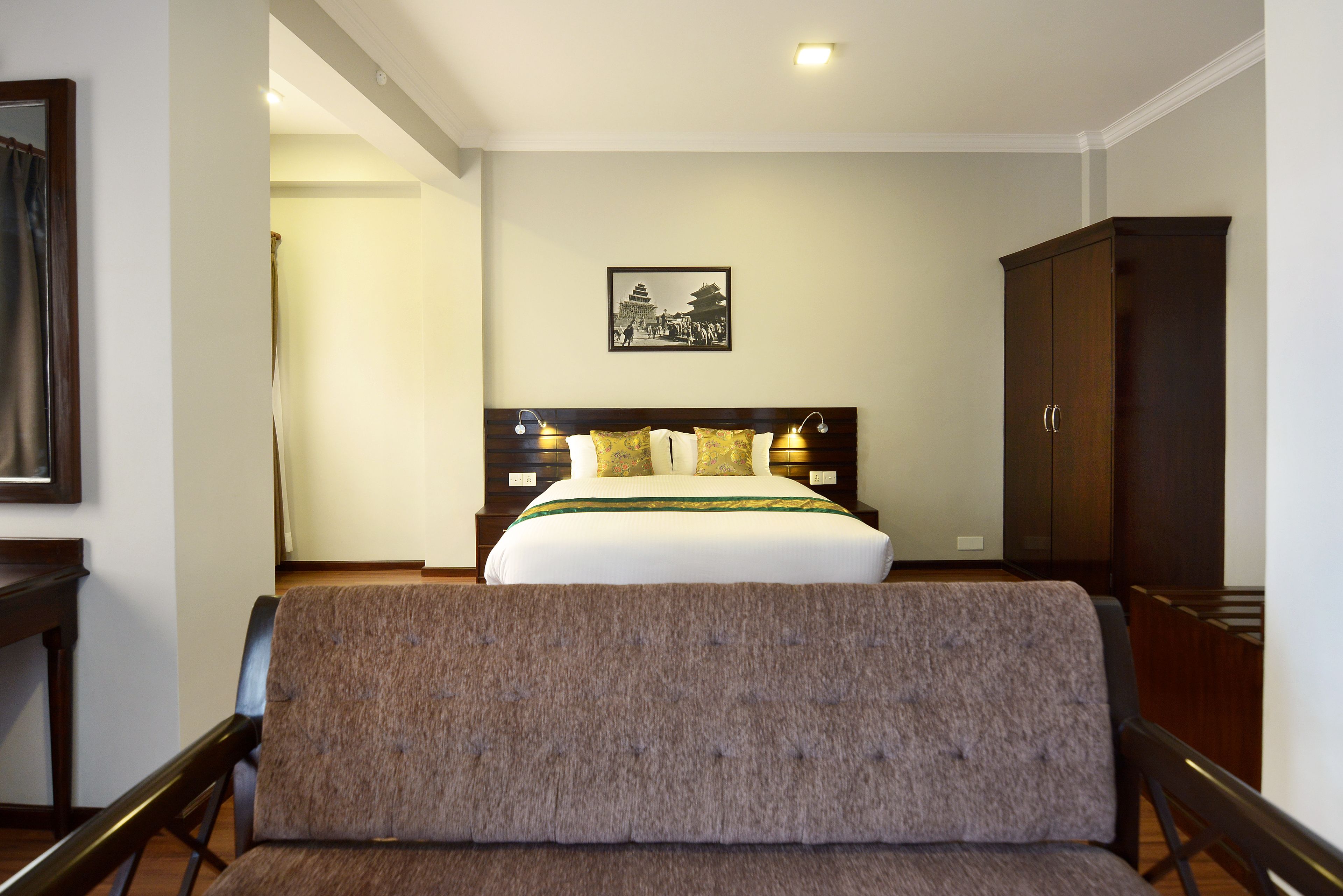 Una camera d'albergo con un letto grande, una testiera in legno, un armadio scuro in legno e un quadro appeso al muro.