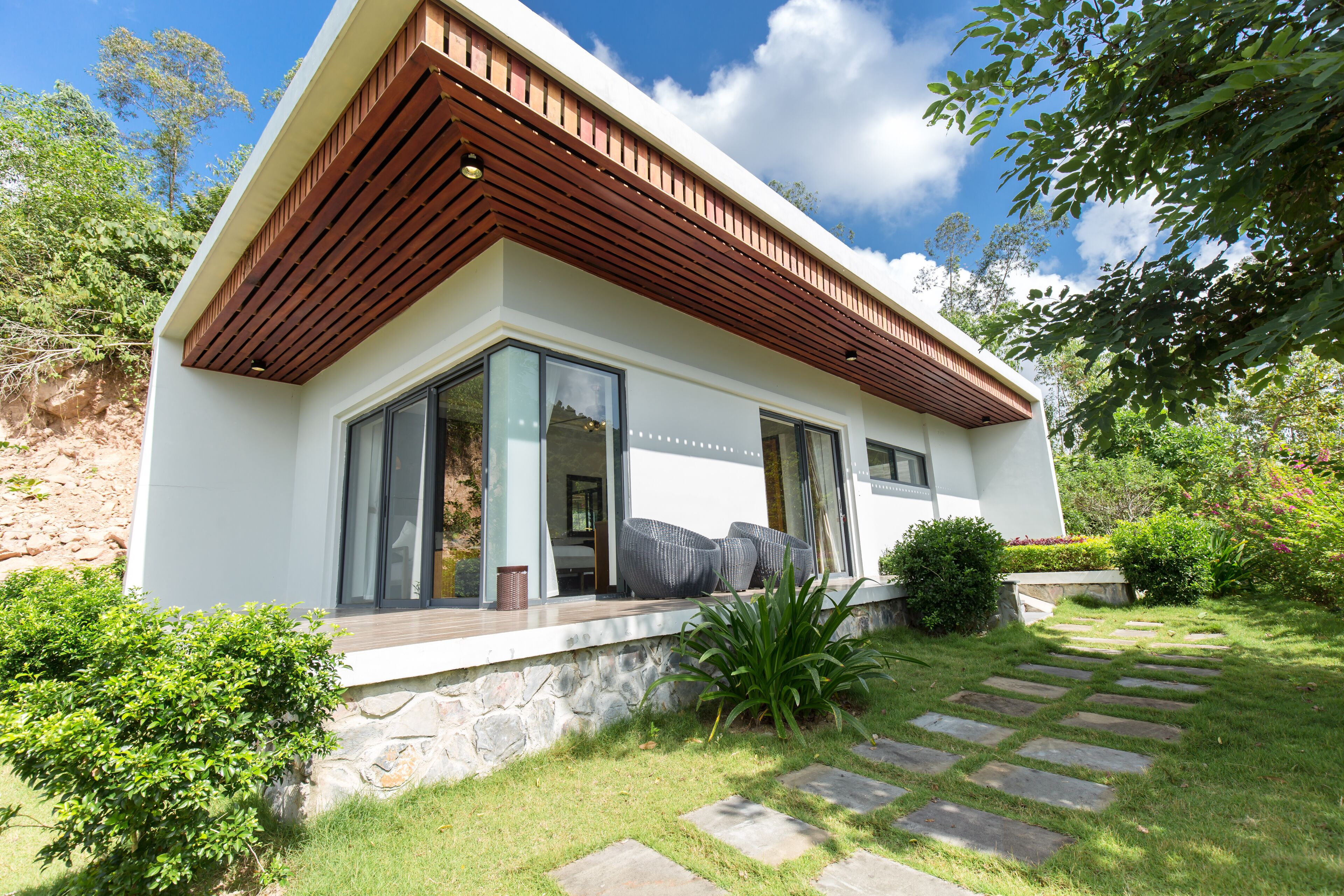 Una casa moderna con base de piedra, ventanas amplias y techo inclinado de madera.