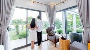 A spacious room with large windows, a comfortable sofa, and a small side table. - Muong Thanh Luxury Dien Lam Hotel (Hung Chau)